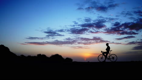 Mountainbiker-Erreicht-Den-Gipfel-Und-Hebt-Sein-Fahrrad-Im-Atemberaubenden-Abendlicht-In-Den-Himmel.